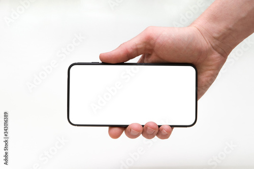 a man's hand holds a smartphone with an empty screen horizontally on a white background, close-up of the hand. Space for text
