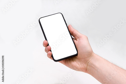Man holding smartphone with blank screen on white background, closeup of hand. Space for text