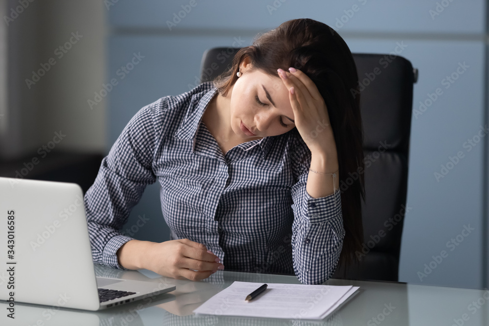 Unhappy attractive businesswoman suffering from headache at work at laptop. Young female employee stressful touching temples thinking about business problem. Unhappy attractive businesswoman suffering from headache at work at laptop. Young female employee stressful touching temples thinking about business problem.