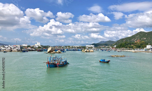 Bright fishing boats in the bay, Vietnam. blue boats with red details. Traditional Vietnamese buildings in the background