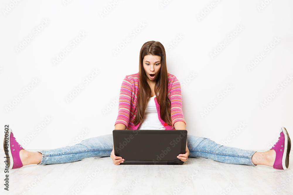 Naklejka premium Woman and Laptop, Stretched Legs Apart, Surprised Astonished Girl with Notebook Sitting on Floor over White