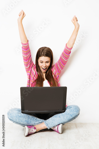 Excited Woman and Laptop Raise Arms, Happy Girl have Success in Computer, Sitting on Floor over White background © inarik