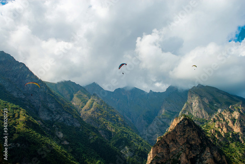 view of the mountains, forest, three paragliders circling in the sky, a clear summer day, chegemsky gorge