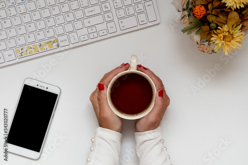 Girl hands around a tea cup at the office at home. Cozy workplace of freelancer and student. Flat lay, top down