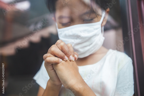 Asian child girl wearing protection mask praying for a new day freedom to coronavirus Covid-19 and stay at home quarantine from the coronavirus Covid-19 and air pollution pm2.5.