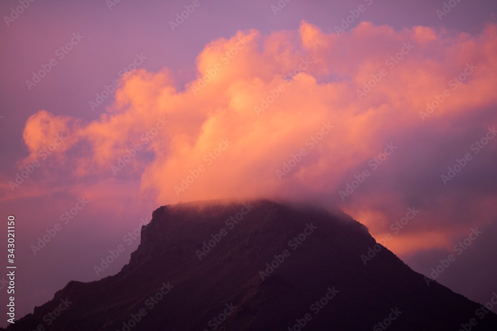 Coloured purple violet sunset at the muntain with white clouds above - beautiful mounts landscape with amazing colors - concept of nature and outdoors