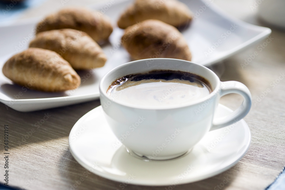 Breakfast, fresh croissants on a plate and a Cup of black coffee Breakfast, fresh croissants on a plate and a Cup of black coffee