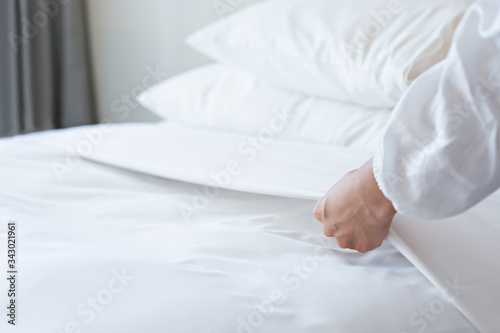 Female Hand set up white bed sheet in bedroom
