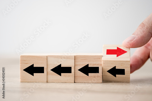 Hand flipping wooden cube block arrow from change left to right for business disruption and different thinking idea.