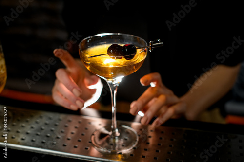 Close-up of glass with cocktail which decorated small sword with cherries