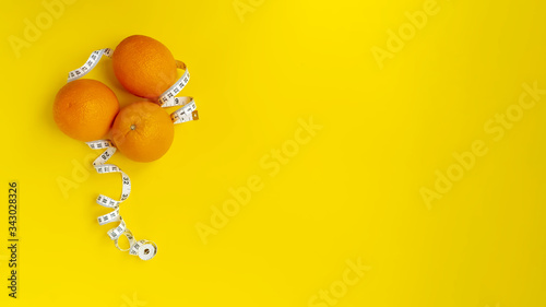 Bright yellow background with oranges and tape. Healthy food concept. Copy space. Place for text and design.