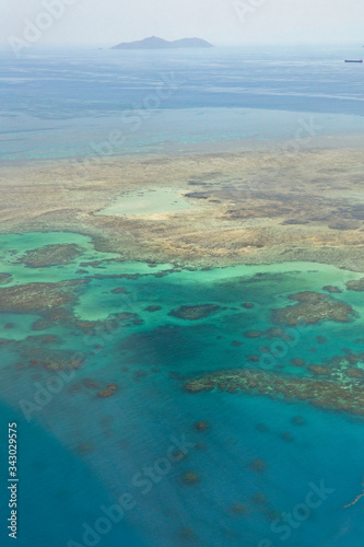 Island in Great Barrier Reef Blue Sea view. Beautiful aqua & turquoise waters, with sand, coral reef patterns in the ocean. View from helicopter, on vacation. Tropical, paradise, holiday concepts