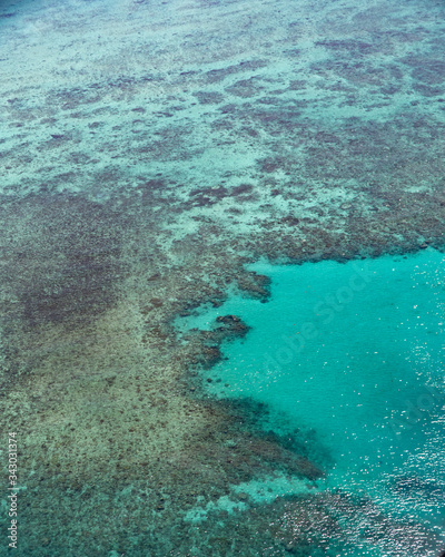 Fototapeta Naklejka Na Ścianę i Meble -  Great Barrier Reef Blue Ocean Sea view. Beautiful aqua & turquoise waters, with coral reef patterns in the ocean. View from helicopter, on vacation. Marine life, global warming, protection, island