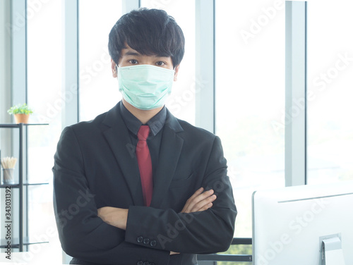 Asian business man or employee is wearing mask for protection from coronvirus or covid-19 or pm 2.5.Man with flu working in the office.