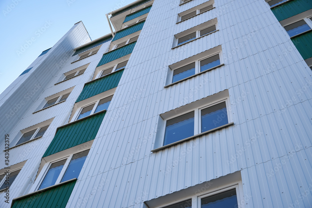 facade of a new multi-storey building with white and green metal siding, many Windows