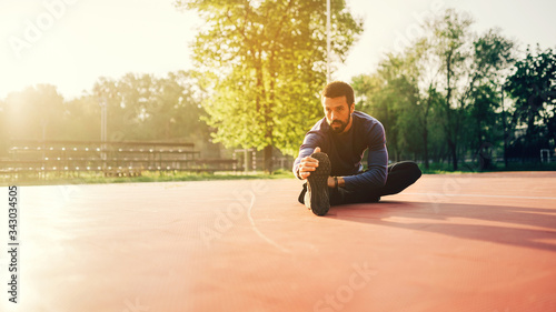 Male doing stretching exercise, preparing for a morning workout in the park