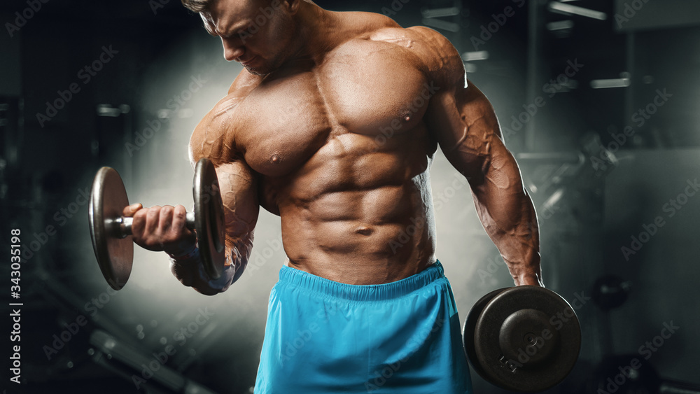 Fotografie Bodybuilder strong man pumping up biceps muscles