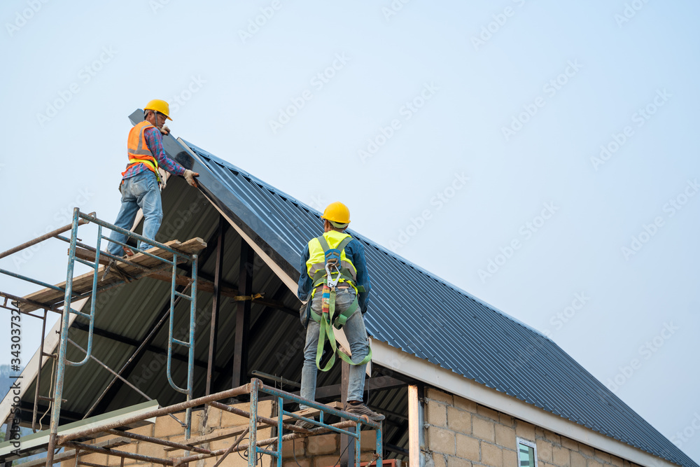 Φωτογραφία Roofer using air or pneumatic nail gun and installing metal roof tile on top roof,Builder Working On Roof Of new building