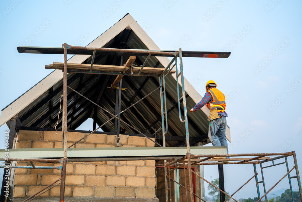 Technician working on roof structure on construction site,Construction worker wearing safety harness belt during working on roof structure of building on construction site.