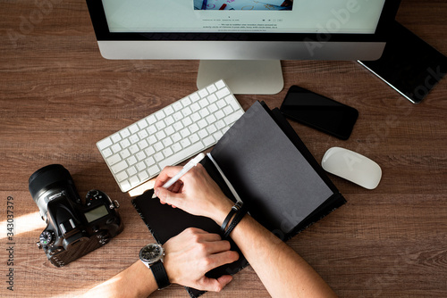 Man writing in a black notebook. Concept man, photographer working from home. Free space for text. view from above.