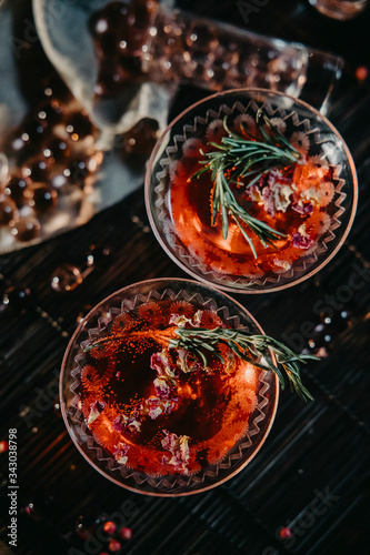 Two-layer cocktail with cranberry vodka, rosemary. Two martini glasses of red alcohol raspberry cocktail 