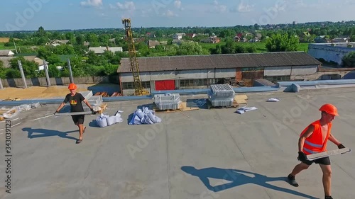 Wallpaper Mural Workers on the roof on the countryside background. Technicians in orange safety helmets carrying equipment for future solar farm. Motion camera back. Aerial view. Torontodigital.ca