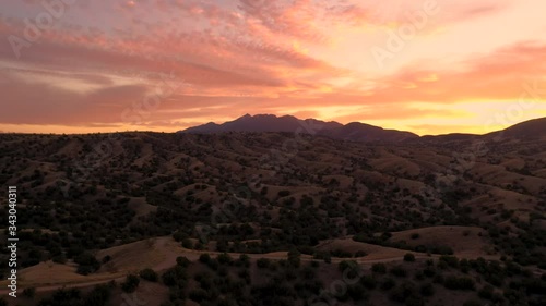 Fiery And Dramatic Sunset In Sonoita Arizona Brown Hills With Santa Rita Mountains In The Background. - Aerial drone ascending photo