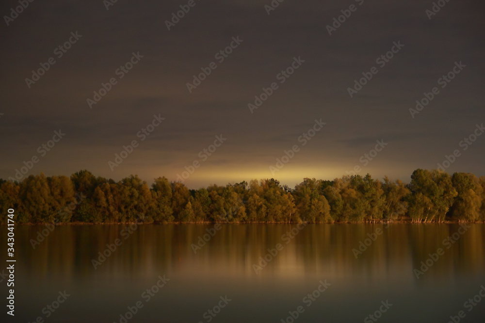 Long exposure landscape photo about Danube river and forest at night; color image.