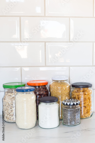 Different food in reused glass jars on the kitchen, zero waste plastic free concept, vertical, copy space