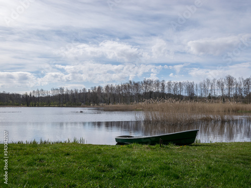 sunny spring day landscape, bright blue sky with white clouds, boats on the shore of the lake