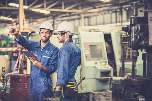 Professional team engineering Man Worker at industrial factory wearing uniform and hardhats at Metal lathe industrial manufacturing factory. Engineer Operating lathe Machinery