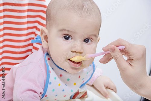 Feeding the baby with a spoon. A mother gives healthy food to her child at home