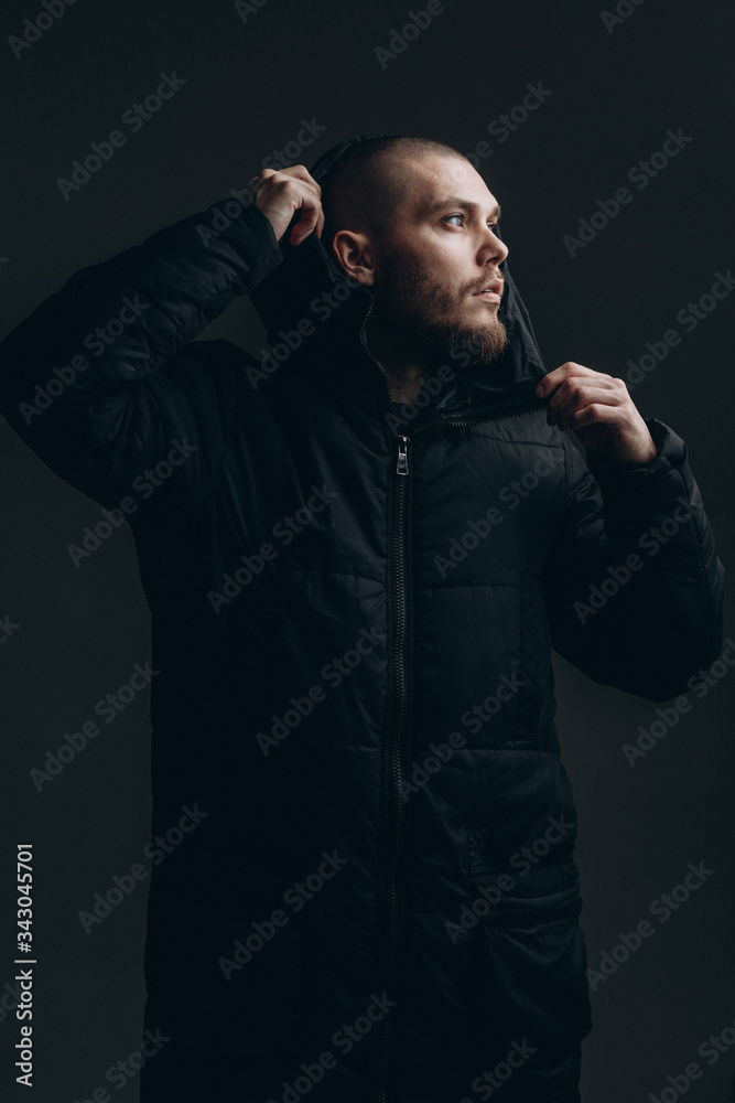 close-up portrait of a serious young man in a jacket looking to the side on a gray background. bald with a beard close-up portrait of a serious young man in a jacket looking to the side on a gray background. bald with a beard