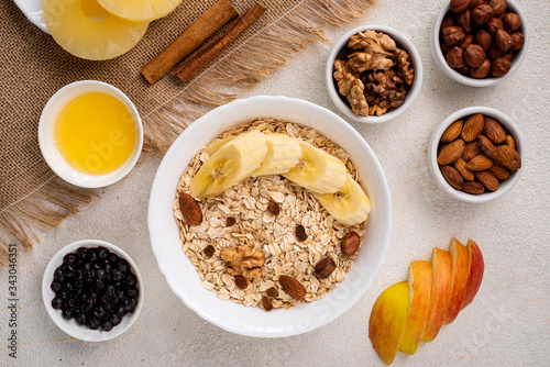 Breakfast oatmeal with fruits, nuts, banana, honey, apple. Healthy breakfast cereal. Top view.