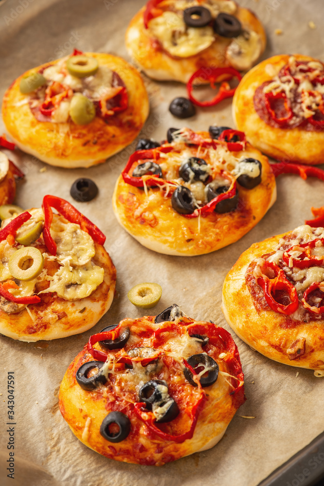Homemade mini pizza with salami, pepper, olives and cheese.