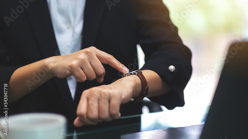 Принти на полотні A business woman pointing at a wristwatch on her working time while waiting for