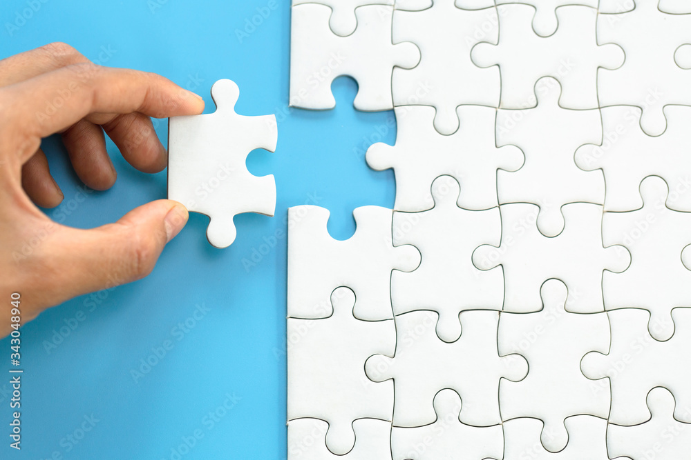 White jigsaw in the hands, The correct solution. Teamwork, Solving and completing the task. Last piece of jigsaw puzzle. Assembling  jigsaw puzzle pieces.