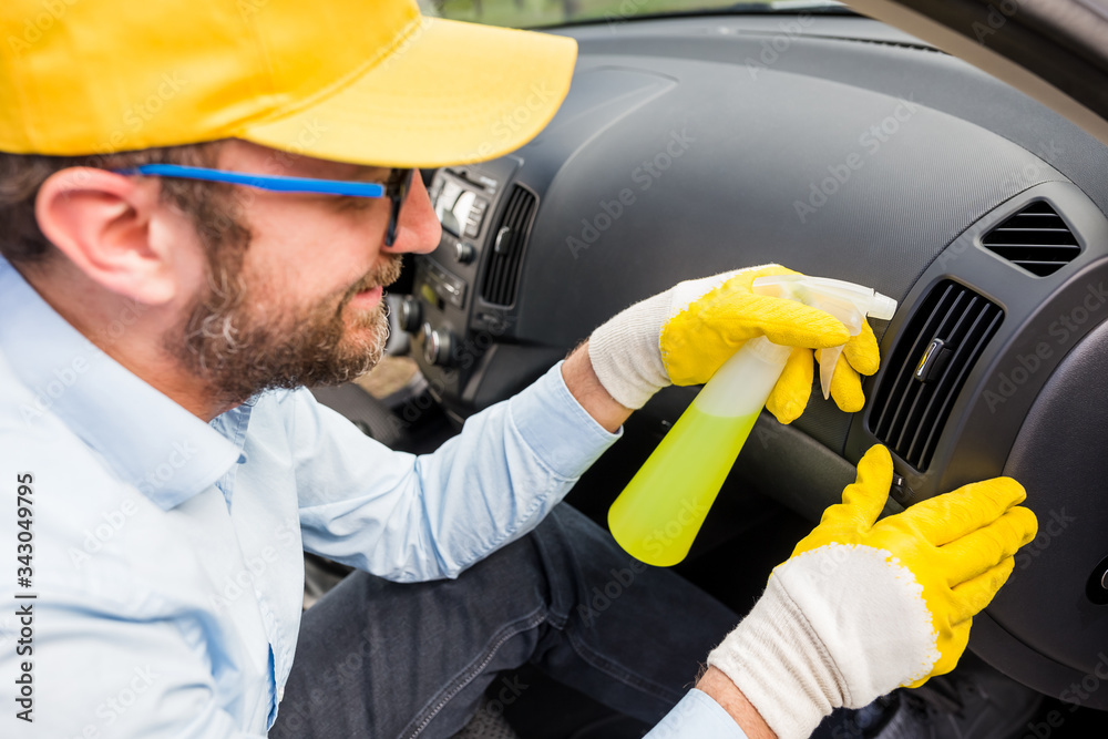 Professional worker using disinfectant to clean car interior dashboard. Professional worker using disinfectant to clean car interior dashboard.