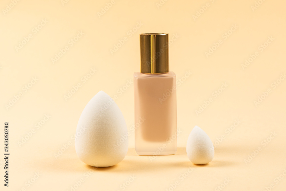 Small, medium and large white beauty blender and makeup foundation on beige background. Small, medium and large white beauty blender and makeup foundation on beige background.