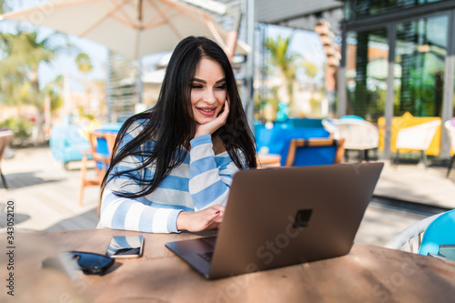 Young attractive woman sitting in a cafe with a laptop