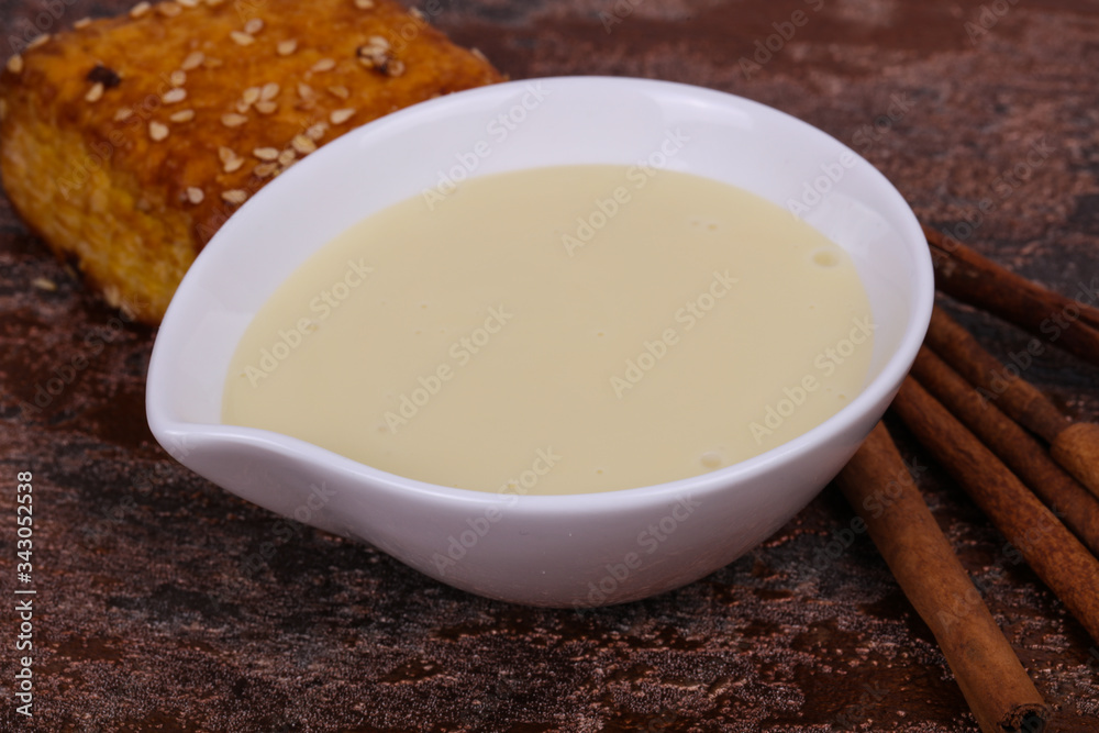 Condenced milk in the bowl with sinnamon and pastry Condenced milk in the bowl with sinnamon and pastry