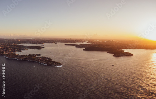 High resolution panoramic sunset aerial drone view of famous Sydney Harbour with the city centre in the background. South Head, a headland to the north of Watsons Bay suburb, in the foreground.