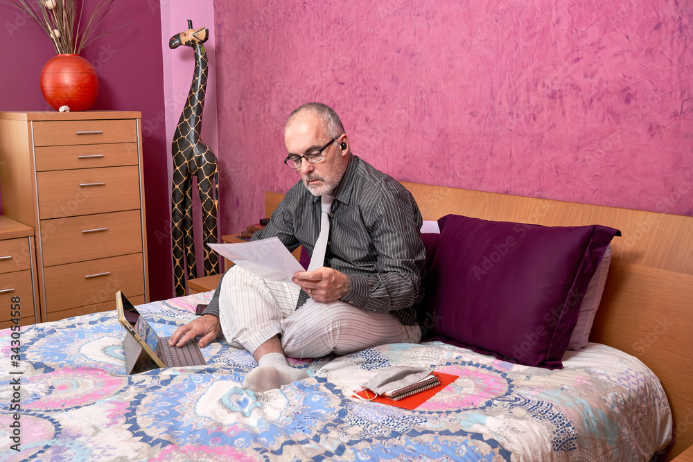 Fototapeta premium Businessman working from home with laptop, wearing shirt and tie and pajamas