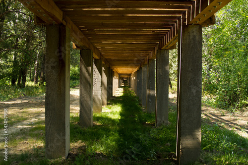 Wooden bridge in the park. The underside on concrete poles.