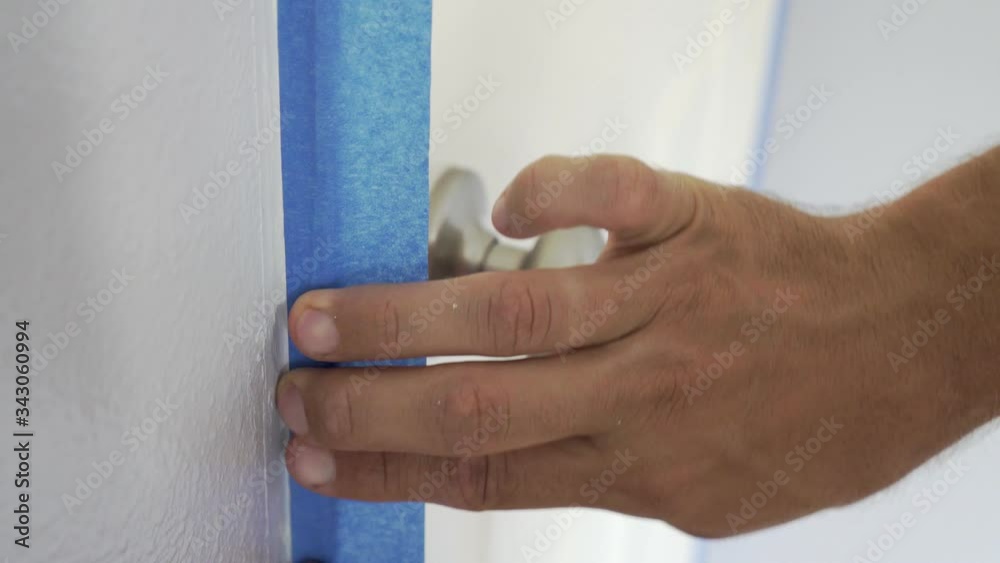 Interior Painter Using Masking Tape to Secure Wooden Window Frame. Interior Painter Using Masking Tape to Secure Wooden Window Frame.
