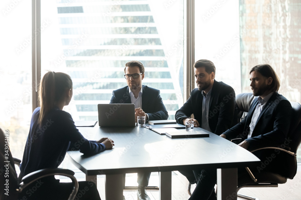 Three confident hr managers holding job interview with candidate, looking at seeker, making decision, sitting at table in boardroom, recruiters asking questions to applicant at meeting Three confident hr managers holding job interview with candidate, looking at seeker, making decision, sitting at table in boardroom, recruiters asking questions to applicant at meeting