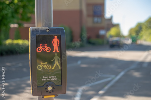 Close up of Traffic Light buttons with blurred cars in the background on a bright sunny day