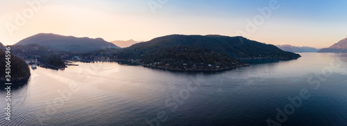 Aerial drone footage of a car ferry boat coming into dock on Bowen Island near Vancouver BC at sunset.