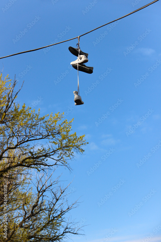 Sneakers hanging on the power line. Dangling shoes have meaning.