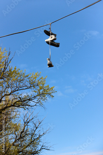 Sneakers hanging on the power line. Dangling shoes have meaning.